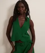 Chaleco corto de viscosa color verde esmeralda, de corte sastre, con escote en V, lazo en la espalda y cierre cruzado con botones.