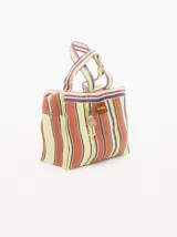 Bolso playero tipo tote bag a rayas horizontales en tonos naranja, amarillo, blanco y violeta. Tiene doble asa corta y cierre superior con cremallera. Incluye un dije colgante y una etiqueta de cuero sintético con el logo de la marca.