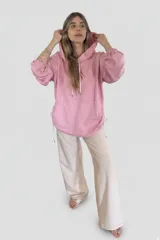 Canguro oversize color rosa con capucha, cordones blancos y bolsillo tipo canguro.