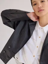 Campera de jean azul con cuello y solapa, corte entallado y largo a la cintura.