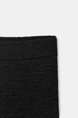 Falda midi negra de tiro bajo, con cintura elástica y tejido con textura estructurada.