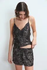 Conjunto de pijama de satén con estampado de leopardo en tonos marrones y negros. Consiste en un top con breteles finos y escote en V adornado con puntilla negra, y un short con cintura elastizada y lazo regulable.