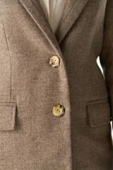 Blazer marrón de lana con solapas de muesca, cierre con dos botones dorados, bolsillos con solapa y forro interior a tono.