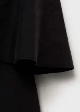 Vestido corto negro de tirantes finos, escote recto y corte ajustado. Presenta un volante superpuesto en el pecho.