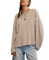 Camiseta de punto waffle color beige, de algodón suave, con silueta relajada, hombros caídos, mangas largas, bolsillo frontal y escote amplio tipo barco.