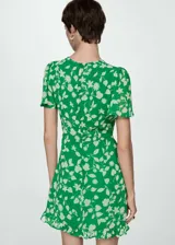Vestido corto negro con estampado de lunares blancos, escote en V con lazo, mangas cortas y falda con volantes.