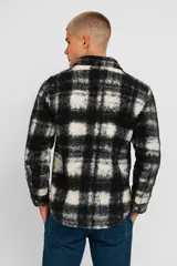 Sobrecamisa de poliéster con estampado a cuadros en blanco y negro, corte holgado, cuello camisero y cierre con botones.