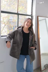 Chaqueta de pana verde con corte amplio, cierre frontal, capucha integrada y bolsillos delanteros. Interior con forro de estampado animal print.