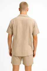 Camisa de lino color crudo, de manga corta, con cuello camisero y bolsillo de parche en el pecho.