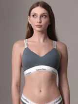 Conjunto de ropa interior Calvin Klein color gris, compuesto por un bralette con copas preformadas, breteles regulables con logo de la marca y cierre trasero con ganchos, y una tanga con cintura elástica con logo de la marca.