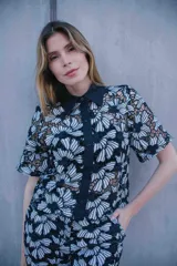 Conjunto de tres piezas con estampado floral blanco sobre fondo negro, compuesto por un top bandeau negro, una camisa de manga corta con cuello solapa y un pantalón largo de corte recto.