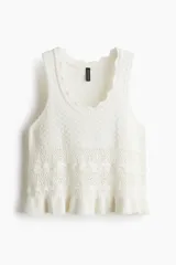Musculosa corta de punto crochet color blanco, con escote redondo pronunciado con ribete festoneado y bajo acanalado de volado. Sin mangas.