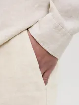 Pantalón chino de lino color beige, corte clásico, con cierre de cremallera y cintura con elástico.