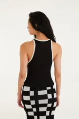 Musculosa negra con tirantes finos y ribete blanco, escote recto y corte ajustado.