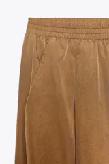 Pantalón de tiro medio color marrón claro, con cintura elástica, bolsillos laterales ocultos y puños elásticos.
