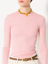 Remera rosa de punto con textura suave, mangas largas, escote redondo y espalda amplia y abierta.