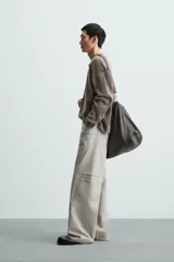 Pantalón de algodón color beige claro, estilo relaxed fit, con cintura ajustable mediante cinturón de tela a juego. Presenta cinco bolsillos, bolsillos laterales de vivo y costuras laterales giradas hacia adelante.