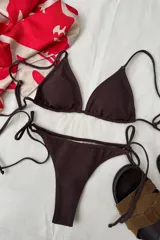 Conjunto de bikini color marrón con lurex, compuesto por un corpiño triangular con breteles regulables y espalda para atar, y una bombacha semivedetina con tiras laterales para atar.