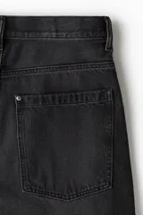 Jean de denim rígido color negro, de corte holgado de cadera a bajo con piernas redondeadas superamplias y pliegues al tobillo. Cintura estándar con cierre y tiro bajo.