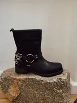 Bota corta negra de cuero con hebillas y arnés metálico.
