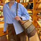 Bandolera de símil cuero con paneles combinados en tonos marrón claro, verde y marrón oscuro. Cuenta con apertura superior con cierre, amplio bolsillo frontal con cierre, tres bolsillos internos (dos con cierre) y un bolsillo trasero con cierre. Incluye correa larga regulable.