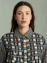 Camisa de diseño único con estampado cuadrillé en tonos sutiles, con vuelos en la parte superior y botones plateados.