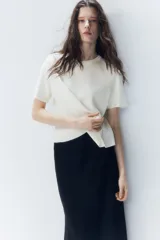 Remera color crudo de punto fino, con cuello redondo y mangas cortas.