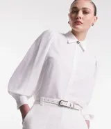 Camisa blanca de crepé con cuello solapa, abotonada, mangas largas abullonadas y sin estampado.