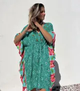 Túnica corta verde con estampado de flores rojas y detalles bordados. Mangas anchas con terminación en volados con estampado floral en tonos rosa y celeste.