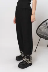 Pantalón negro de simil lino, con elástico en la cintura y bordados en la parte inferior.