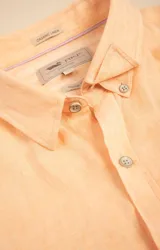 Camisa de manga larga color durazno, confeccionada en lino orgánico, con cuello italiano, cierre con botones y bolsillo en el pecho con logo bordado al tono.