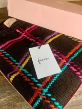 Sweater de lana tejido a mano con diseño geométrico multicolor sobre fondo negro, de calce holgado, cuello redondo y puños ajustados.