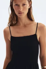 Vestido midi negro con breteles finos ajustables, escote recto, cuerpo ajustado con punto smock y falda con vuelo.