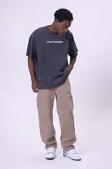 Camiseta de manga corta, color gris oscuro con efecto lavado, corte oversize y cuello redondo. Presenta texto estampado en blanco en el pecho que dice "CREW MEMBER".