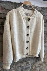 Cardigan color crema de lana merino con botones marrones.
