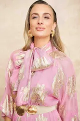 Vestido largo color rosa con estampado dorado, cuello con lazo y mangas largas.
