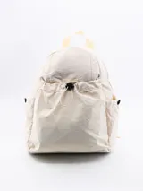 Mochila de tela color crema con bolsillo frontal con cordón ajustable, bolsillos laterales y correas de tela.
