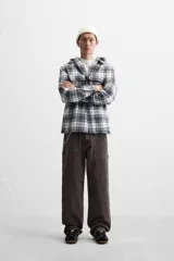 Sobrecamisa relaxed fit de algodón a cuadros azul marino y blanco, con capucha gris combinada a contraste, manga larga con puños abotonados, bolsillos plastrón en el pecho, bolsillos laterales en la cadera y cierre frontal con botones.