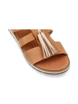 Sandalia de cuero color crema, con tiras cruzadas y detalle de flecos marrones en la parte delantera.