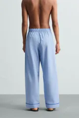 Pantalón de pijama celeste de algodón, corte relaxed fit, con cintura elástica ajustable con cordón interior, bolsillos laterales y detalle de vivos combinados a contraste en el bajo.