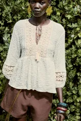 Blusa rústica color crema de cuello redondo con cordón, escote pico y manga larga acabada en elástico. Detalle de tejido combinado en crochet en mangas y parte superior del frente.