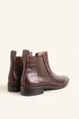 Bota tipo Chelsea de cuero vacuno con textura de efecto croco en color marrón oscuro. Presenta paneles elásticos laterales y una tira de ajuste en la parte posterior, con un taco bajo cuadrado.