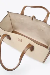 Bolso maxi shopper de hombro color beige con detalles en cuero marrón. Tiene doble asa de cuero y bolsa de tela extraíble con cierre fruncido.