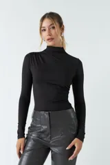 Body negro de poliéster y spandex, con cuello alto tipo polera, mangas largas y frunces laterales.