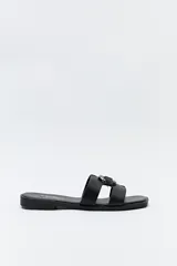 Sandalias planas negras con capellada ancha y herraje metálico central.