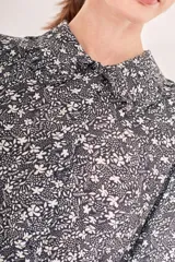 Vestido corto con estampado floral en blanco y negro, cuello camisero, mangas largas abullonadas y falda evasé con detalle de borlas.