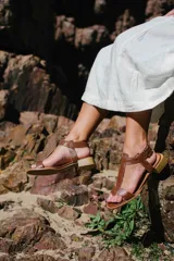 Sandalias de cuero doradas con tiras finas, suela plana y hebilla lateral.