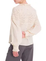 Blusa beige de algodón orgánico con cuello alto y detalles de broderie en la parte superior.