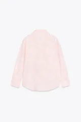 Camisa manga larga color rosa pálido con cuello solapa y cierre frontal con botones. Detalle de bordados perforados engomados con motivos florales. Corte recto.