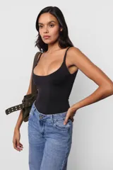 Body negro ajustado al cuerpo, con escote redondo y breteles finos. Tiene broches snap en la entrepierna y logo estampado en la espalda.